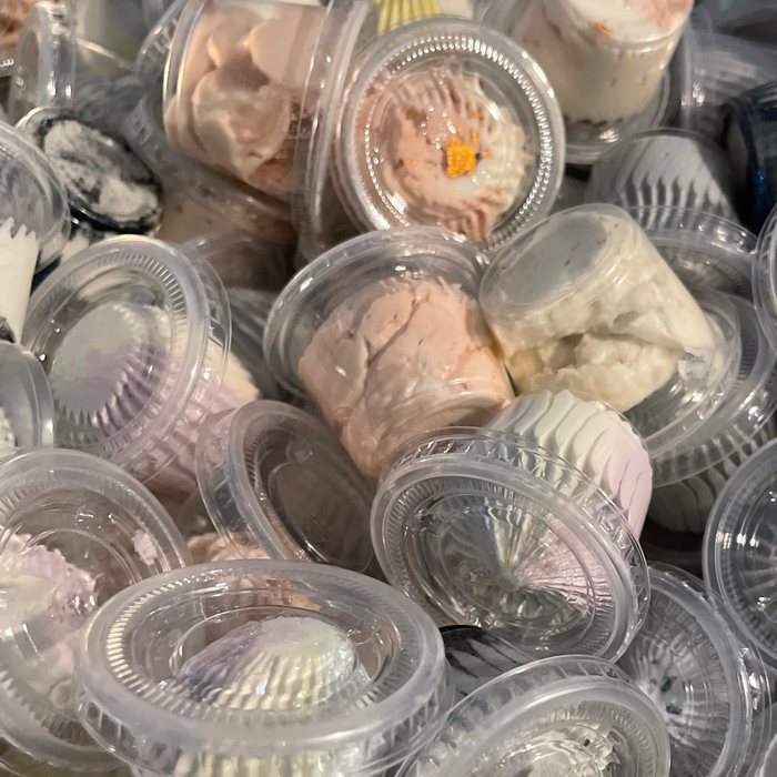 A bowl of small cups of whipped butter in many colors